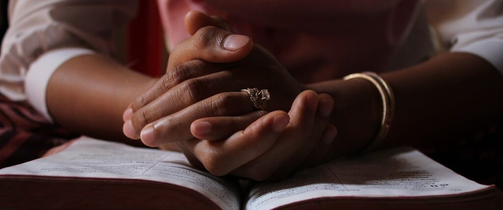 Praying hands resting on a bible